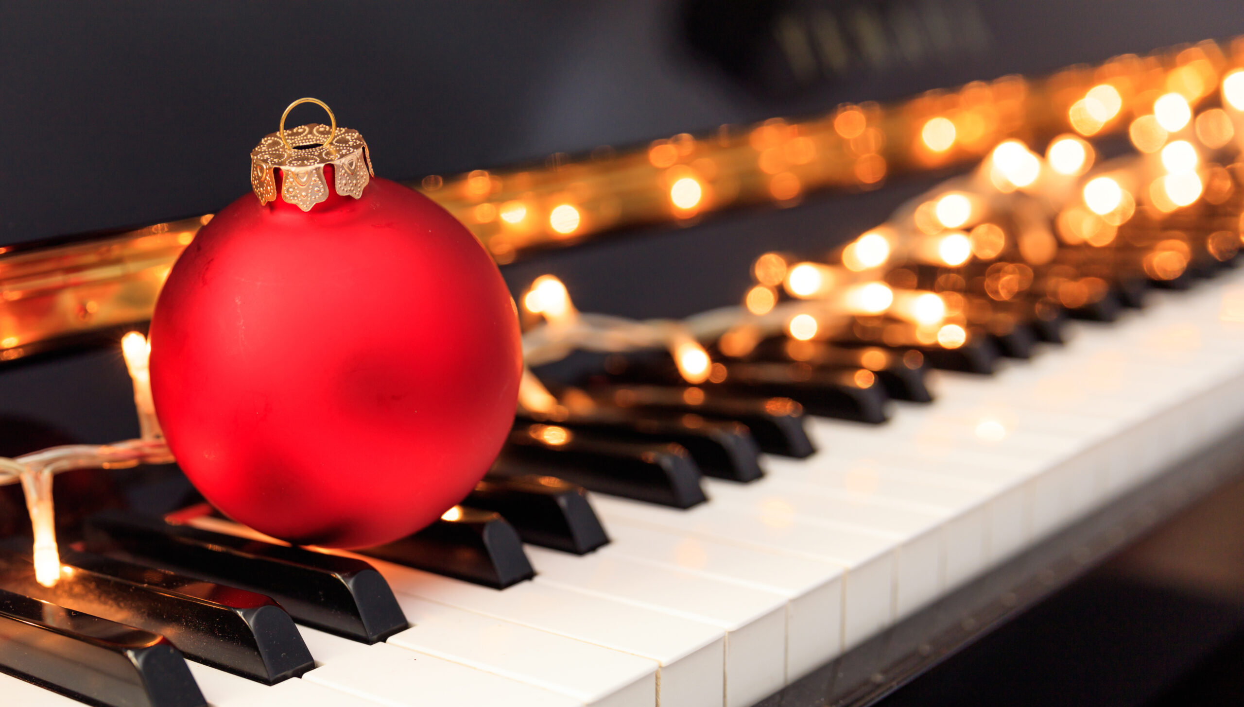 Christmas ball and lights on a classical piano keyboard,